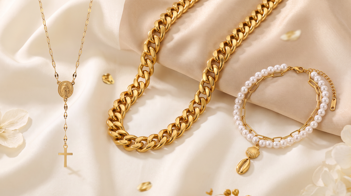 Collares dorados de cadena fina y eslabones, junto a pulsera de perlas blancas sobre tela beige