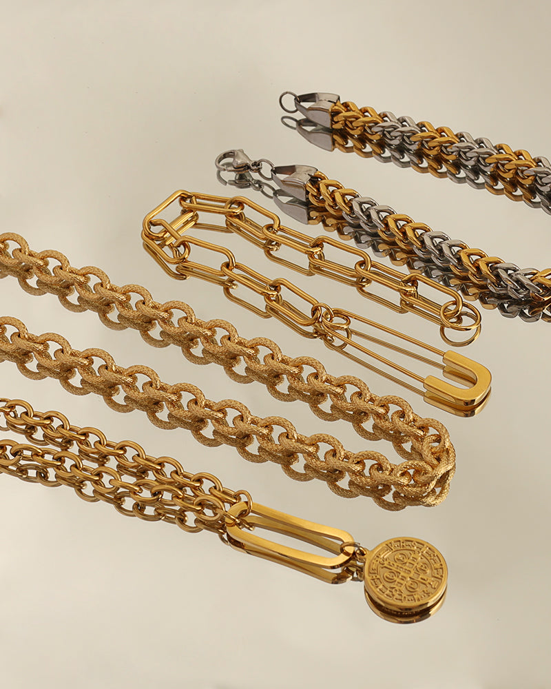 Varias pulseras de cadenas doradas y bicolores sobre fondo claro, una con medallón redondo colgante.