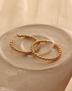 Detalle de aretes Arco con acabado dorado