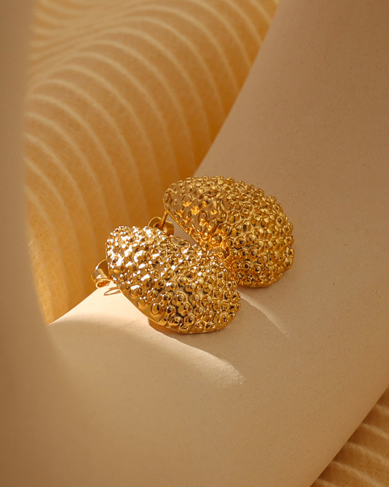 Aretes Lucero de Xihe By Dm, diseño dorado redondeado y abombado con textura granulada, elaborados en acero inoxidable 316L con recubrimiento PVD Oro 18K, de acabado brillante y elegante.