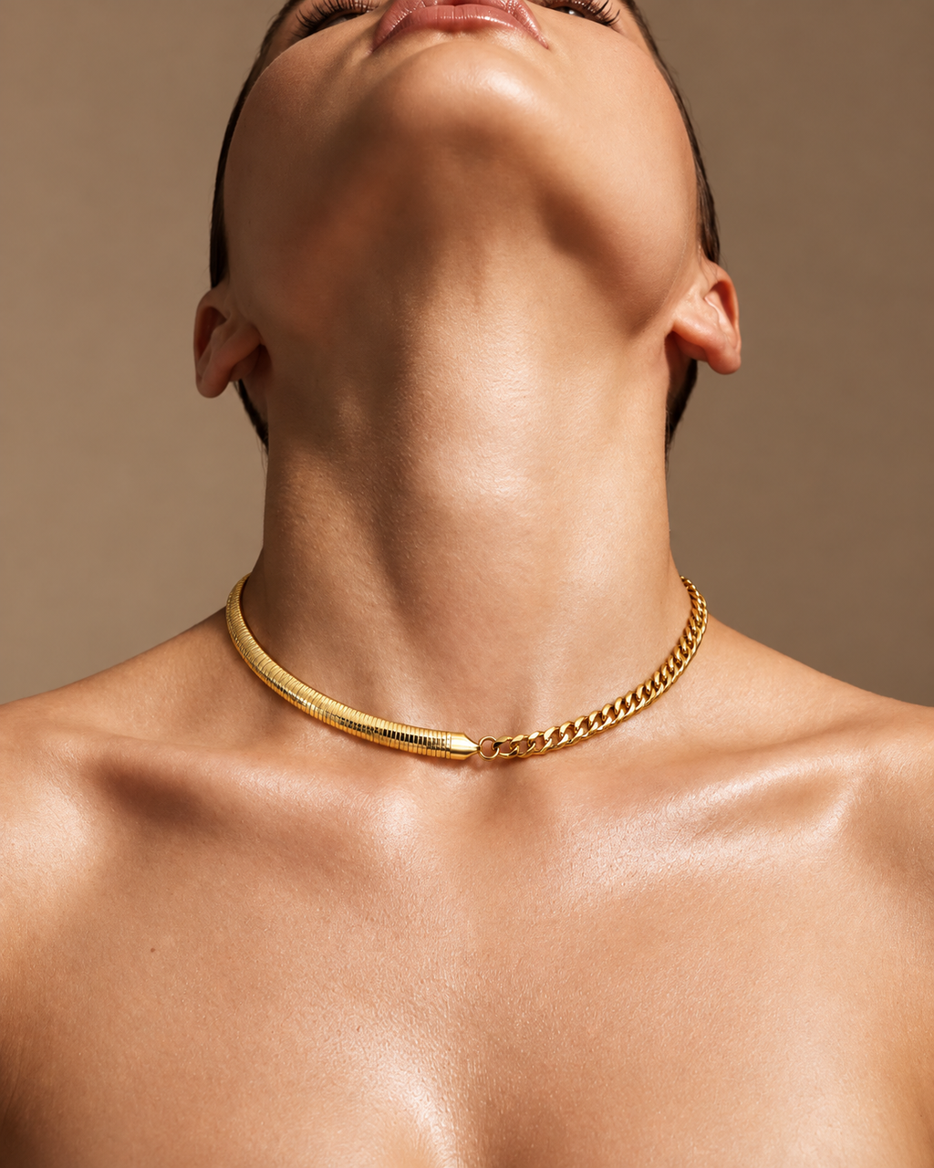 Persona con collar corto dorado que combina cadena plana y eslabones, con la cabeza inclinada hacia atrás.